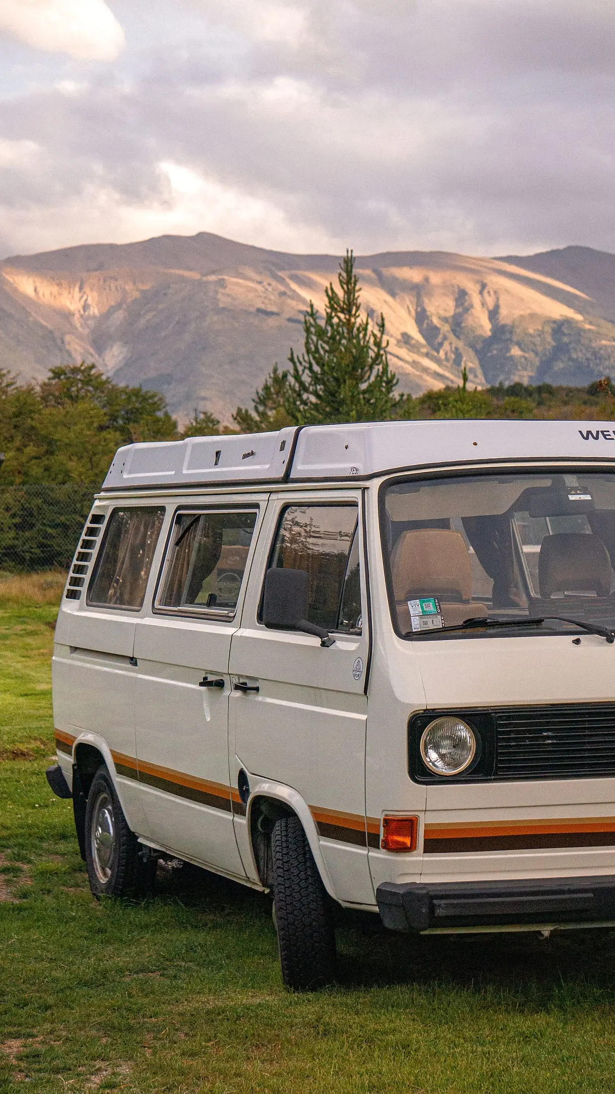 VW T3 Westfalia auf einer Wiese vor Bergkulisse im Abendlicht